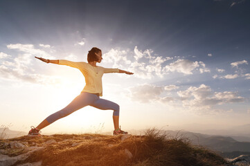 young woman practices yoga and fitness outdoors in a beautiful mountain landscape. Morning dawn,...