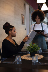 Beautiful young African waitress attending to a client