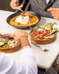 people eating in a restaurant with hands picking up foods 