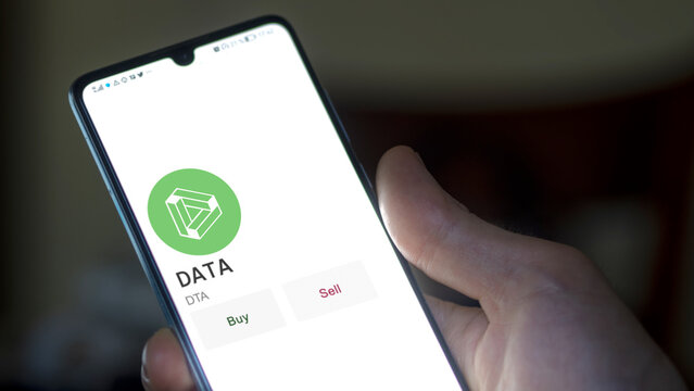 March 11 2023 London UK. An investor's analyzing the DATA  coin on screen. A phone shows the crypto's prices to invest in DTA
