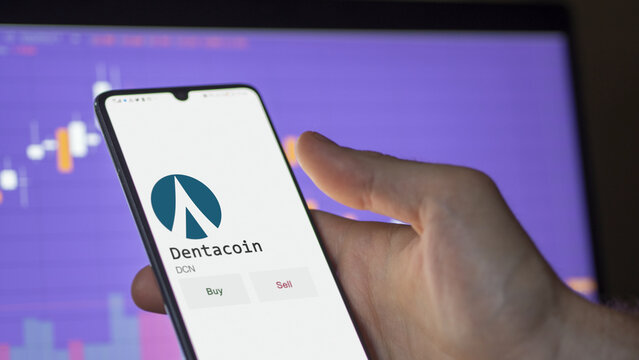 March 11 2023 London UK. An investor's analyzing the dentacoin  coin on screen. A phone shows the crypto's prices to invest in DCN