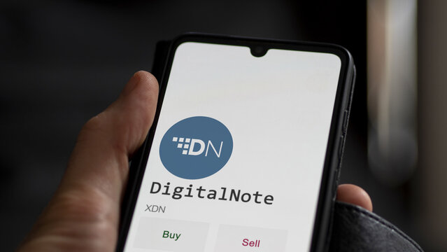 March 11 2023 London UK. An investor's analyzing the DigitalNote  coin on screen. A phone shows the crypto's prices to invest in XDN