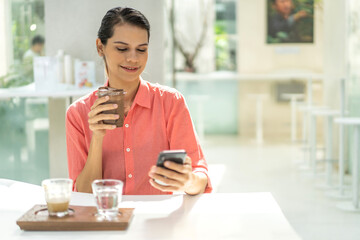 Portrait of smiling happy beautiful woman relax use digital network smartphone.Young girl looking at screen typing message and playing game online or social media at cafe,online banking,payment