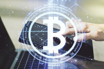Double exposure of creative Bitcoin symbol hologram and hand working with a digital tablet on background. Mining and blockchain concept