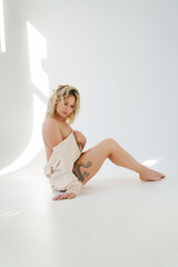 a gentle naked blonde woman in a white shirt on the floor. 