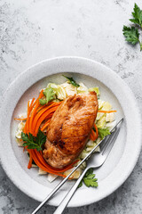 Roasted chicken breast and fresh salad with cabbage and carrot on plate, top view