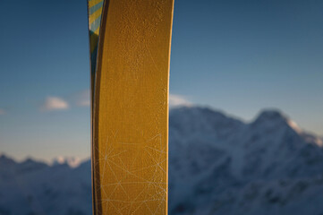 close-up of skis standing against the background of blurry snow-covered steep mountains. close-up...