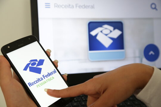 Declara&ccedil;&atilde;o de imposto de renda da receita federal no brasil com celular e computador no fundo.
