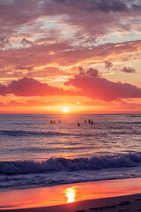 Fototapeta premium Beach view with surfers in the ocean at sunrise. Gold Coast, Australia