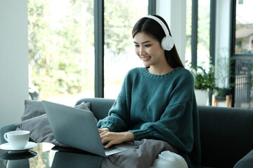 Happy young woman in headphones speaking looking at laptop making notes. Girl student talking by video conference call. Female teacher trainer tutoring by webcam. Online training. E-coaching concept