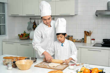 Young handsome asian man chef cooking breakfast in the kitchen. Happy asian man preparing food with ingredient. Chef in uniform in the kitchen.