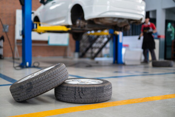Auomobile repair, Used car tires on epoxy floor in auto workshop, Vehicle raised on lift at...