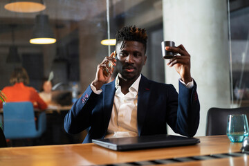 Portrait of successful businessman in office. Young smiling man talking to the phone