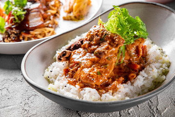 Spicy chicken cooked with curry sauce and rice in bowl