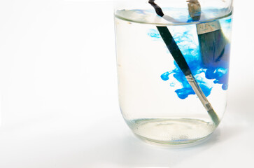 Paintbrush with Watercolor in glass bottles Soft-focus image on a white background.