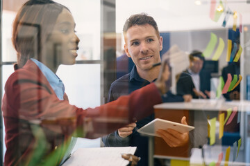 Obraz premium Positive multiethnic colleagues in formal clothes standing near