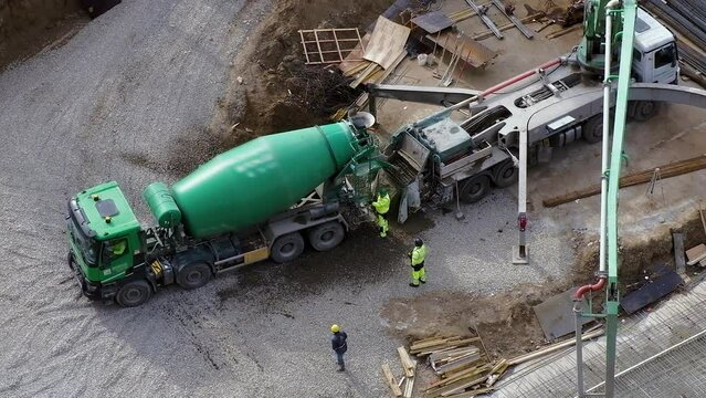 Top view: green concrete mixer at construction site, workers around.