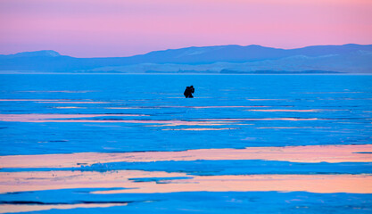 Photographer shoots a sunset among the snow-covered hummocks of Lake Baikal