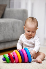 Obraz premium Cute baby girl playing with colorful toy pyramid
