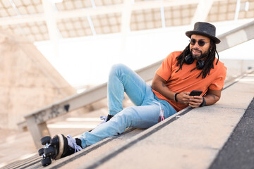 Fototapeta premium Black man enjoy outside. Modern man posing with roller skates..