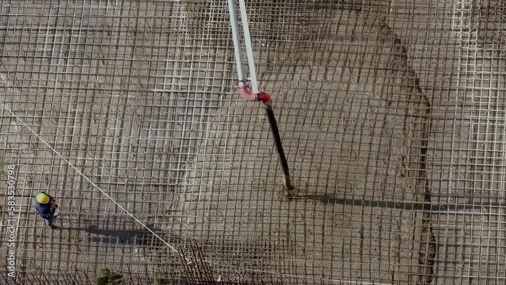 Wall mural Worker looks at pouring concrete into a foundation at construction site