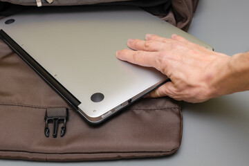 man takes laptop out of travel bag