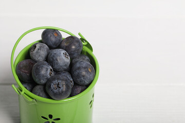 Light green decorative bucket with large blueberries. International day without diets. On a white background. Close-up.