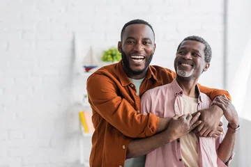 Foto op Plexiglas Cheerful african american man hugging mature dad and looking at camera at home. © LIGHTFIELD STUDIOS