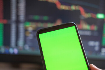 Black phone with blank mockup screen on rising stock graph. Closeup hand showing smartphone isolated green display. Online banking, Fund App use. Financial analyst on Invest Market. Bank collapse 2023