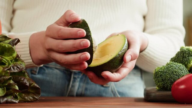 Woman opening avocado in kitchen, Food shopping delivery, online shop. Buying eats in supermarket store. Green basket with fresh vegetables, goods products top view,