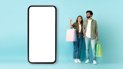 Multiracial couple showing nice shopping mobile app, copy space