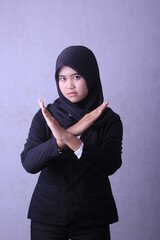 A young woman wearing a hijab with her hands crossed and the word no on her chest