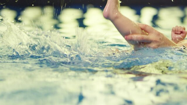 Father holding little baby and helping to swim in swimming pool with clean blue water. Professional water therapy for kids . Swimming training from an early age . Parent having fun . Happy lifestyle