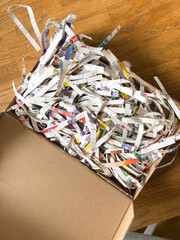 A close-up of a chaotic heap of shredded newspaper, cardboard and other recycled materials in an overflowing wastepaper basket