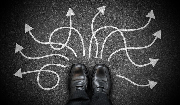 Black business shoes and many winding chalky arrows on asphalt - decision concept