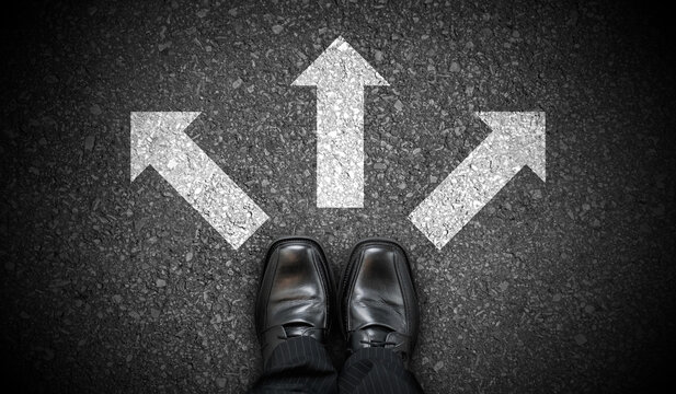 Black business shoes and three chalky arrows on asphalt - decision concept