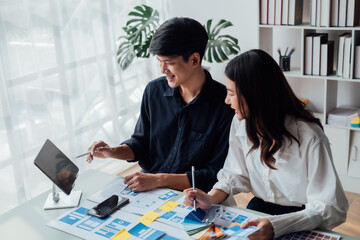 Fototapeta premium Man and woman ecommerce business workers using smartphone and Chart plan at the office.