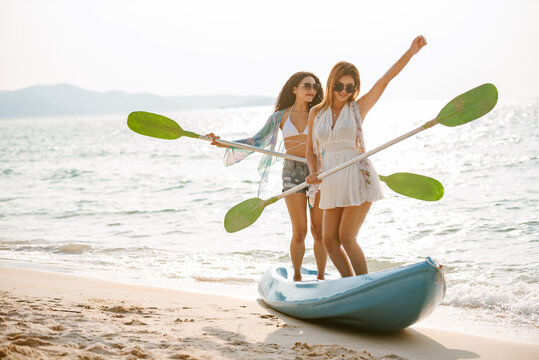 Happy women enjoying outdoor activity on the beach, Young adult female having fun kayaking at the sea for relaxing on vacation summer. Travel and holiday concept.