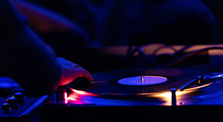 Consular DJ detail with selective focus on turntable while mixing in a concert