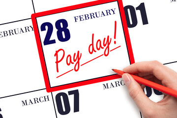 Hand writing text PAY DATE on calendar date February 28 and underline it. Payment due date