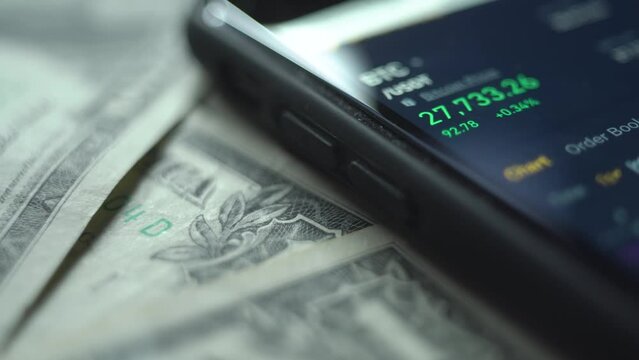 Real-time analysis of the cryptocurrency market in a smartphone. dollar bills. close-up.