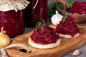 Homemade spicy caviar from beets, carrots, onions and garlic on toasted bread and also in jars on...