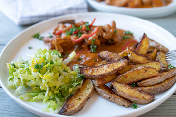 Potato wedges with chicken, sauce and salad on a plate