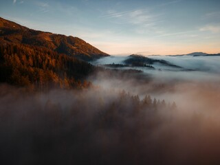 Fototapeta na wymiar Scenic aerial view of forests and mountains on a foggy day in Mariazell city, Austria