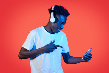 Cool black guy using wireless headset and smartphone