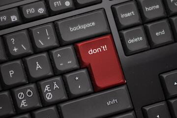 Computer keyboard with a red button saying don’t.