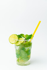 Vertical shot of a fresh lime lemonade in a to go plastic glass with mint.