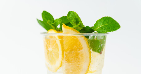 Close up shot of a fresh lemonade in a to go plastic glass with mint leaves.