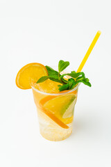 Vertical shot of a fresh orange lemonade in a to go plastic glass with mint.