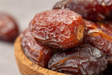 Closeup of delicious dried dates in a wooden bowl.